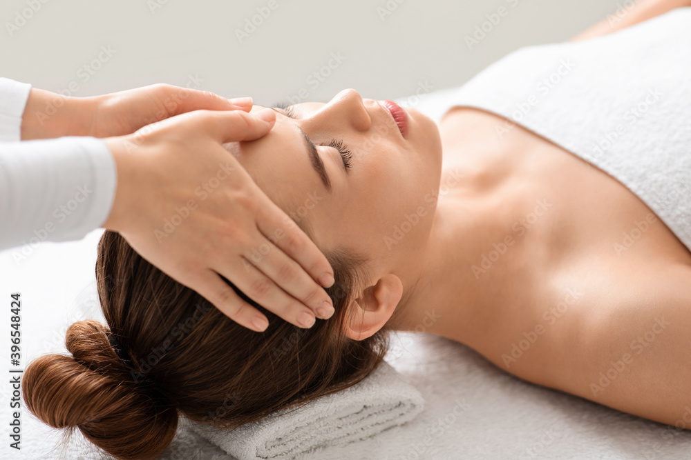 Spa attendant making healing head massage for young beautiful woman Spa attendant making healing head massage for young beautiful woman