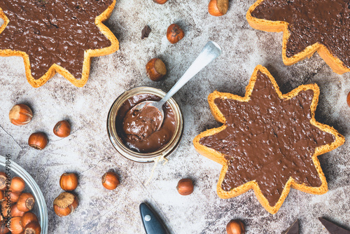 Homemade hazelnut chocolate butter in a jar and spread on star shaped pieces of pandoro panettone.