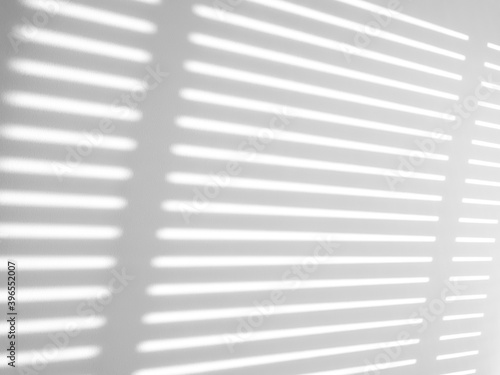 Abstract shadow and sunlight shining through blinds, White wall minimalist style.
