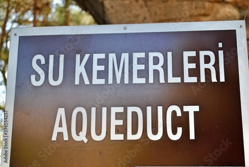 Signpost direction to Aqueduct,. ancient water supply at the ruin ancient city of Perge, near Antaliya, Turkey, where tourist related signs use a brown background with white letters. photo