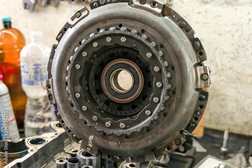 A dirty clutch basket rests on a disassembled engine.