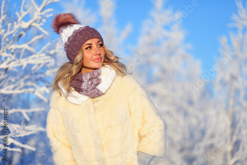Young woman in a warm knitted hat and a snood in the winter forest