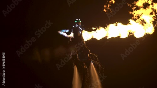Spectacular night show on the water. A flyboarder with a flamethrower flies over the sea. photo