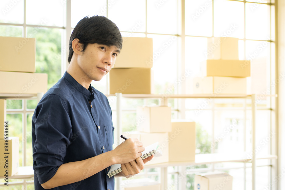 Young man starts small business (SME) by delivering products packed into boxes through a logistics system from home office, package delivery, online marketing,  e-commerce concept.