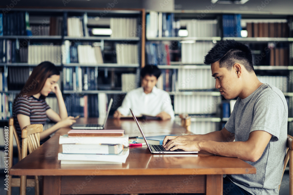 male asian student studying and reading book in library male asian student studying and reading book in library