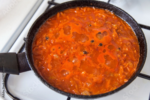 Homemade Tomato Sauce with vegetables simmering in frying pan on stove