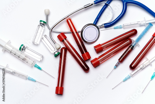 medical ampoule vials, test tubes, syringes and stethoscope over light grey or white background