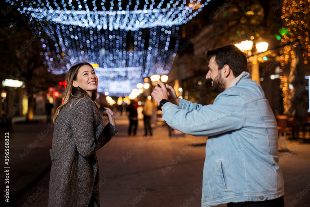 Fototapeta premium Young smiling couple having fun during the winter holidays on the street.
