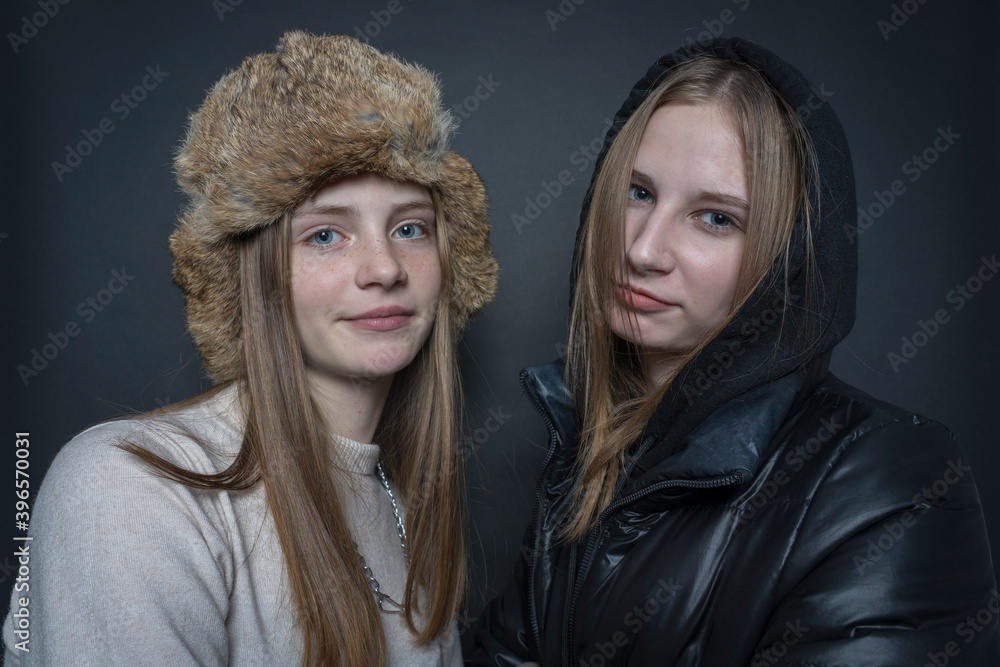 Fototapeta premium Portrait of two beautiful young girls indoors on a black background