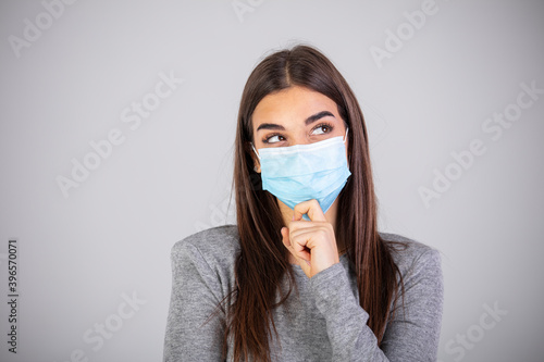 Studio portrait of woman wearing face medical mask, looking at camera, isolated on gray background, close up. Flu epidemic, dust allergy, protection against virus. Covid-19, coronavirus pandemic