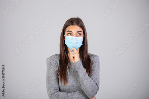 Beautiful caucasian young woman with disposable face mask. Protection versus viruses and infection. Studio portrait, concept with gray background. Girl in respiratory mask.