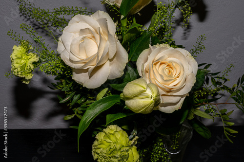A bouquet of funeral flowers. White and yellow flowers with a gray wall background