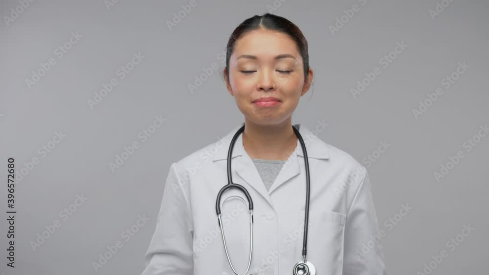 medicine, profession and healthcare concept - portrait of happy smiling asian female doctor in white coat with stethoscope having video call or online consultation over grey background medicine, profession and healthcare concept - portrait of happy smiling asian female doctor in white coat with stethoscope having video call or online consultation over grey background