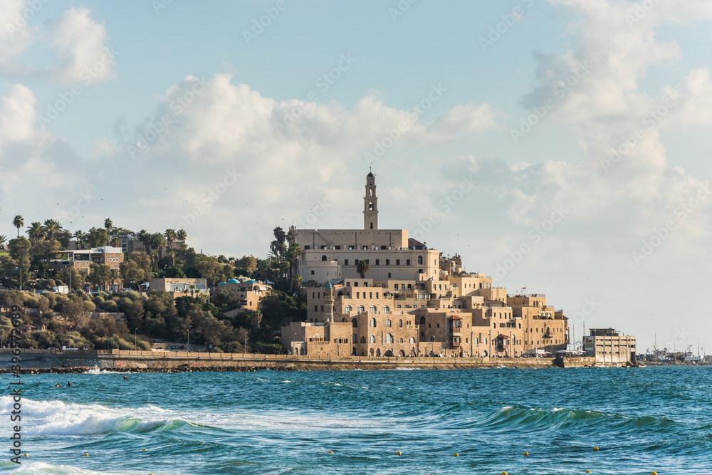 Old Jaffa city, old port and coastal line of Tel Aviv under sunset and lots of tourists are swimming and surfing at the Mediterranean sea.