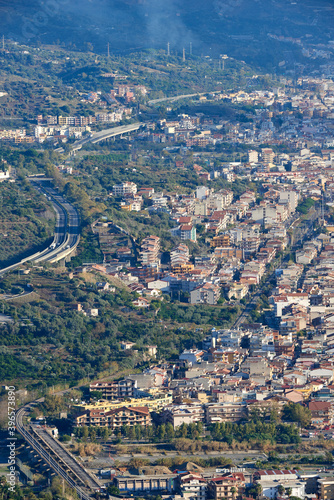 the eastern coast of Sicily seen from above with its towns  roads  railways  buildings and highways on a partially covered autumn day