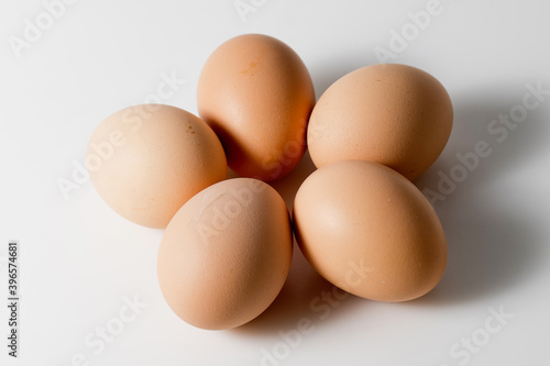 Five brown organic fresh raw eggs. Cut out and isolated on white background with soft shadows for added dimension.