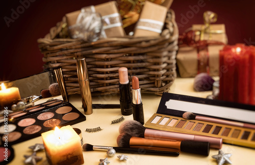 Makeup on the table for the New Year's Eve with a candle and gifts in the background.