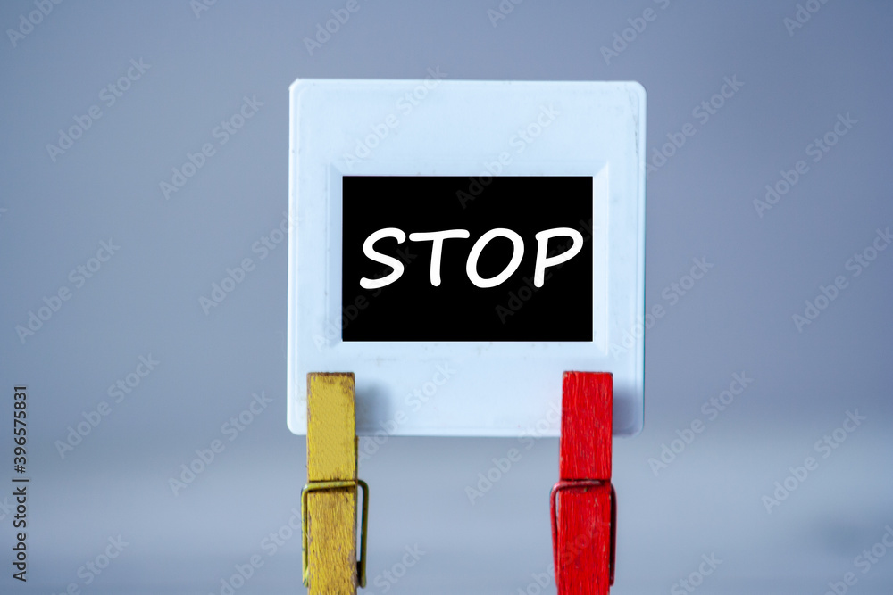 Plastic frame with clothes pin on table. White frame with black background and inscription word STOP. STOP Plastic frame with clothes pin on table. White frame with black background and inscription word STOP. STOP