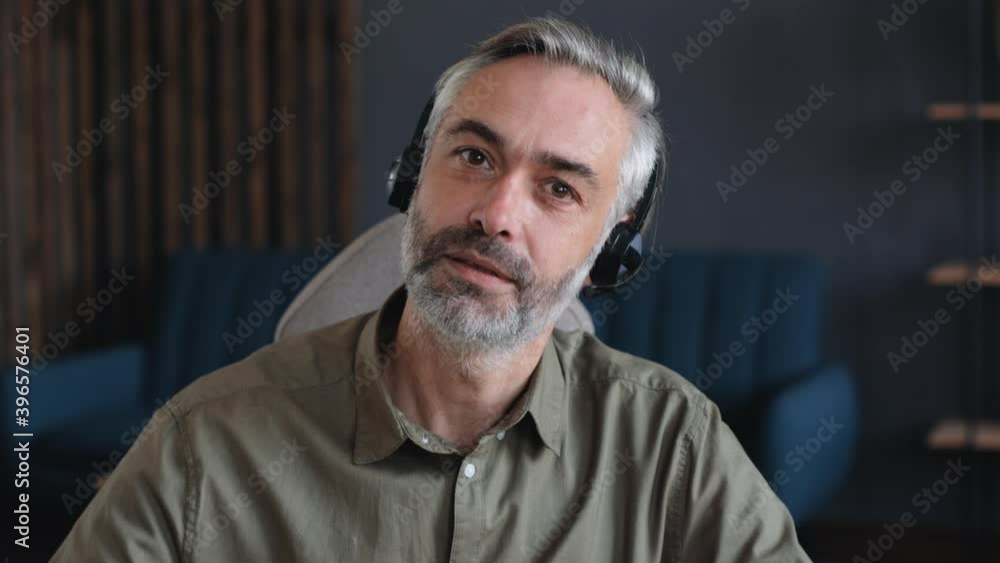 Front View, Close Up of Successful Mature Businessman, Mentor, Coach, Teacher holding Video-Call Class. The Man is wearing a Headset, holding a Seminar, Conference, Webinar. Online Job, Indoor. Front View, Close Up of Successful Mature Businessman, Mentor, Coach, Teacher holding Video-Call Class. The Man is wearing a Headset, holding a Seminar, Conference, Webinar. Online Job, Indoor.