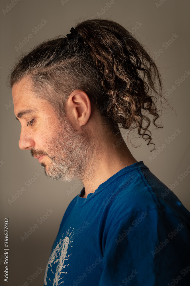 Fototapeta premium hombre de pelo largo con rulos y rapado al costado mira para abajo pensativo