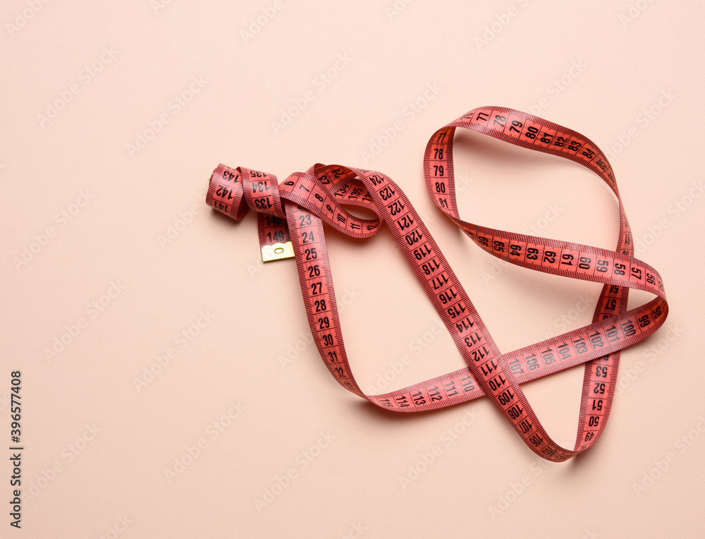 twisted white measuring tape on a beige background twisted white measuring tape on a beige background