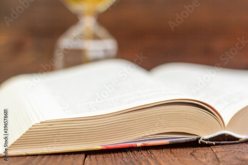 A large hardcover book lies open on an old wooden background.Close up.