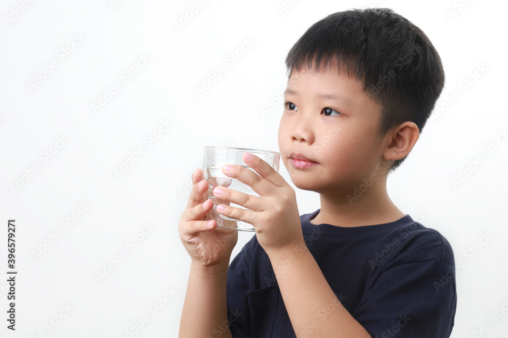 Young Asian boy drinking a glass of water, standing against a white background. Young Asian boy drinking a glass of water, standing against a white background.