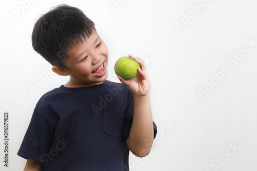 Portrait of a 9-year-old Asian Boy eating apple against a white background