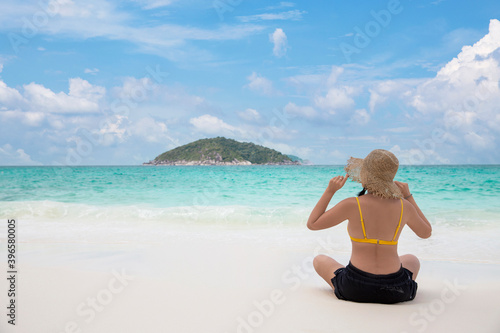Woman bikini relaxing from behind wearing sun straw hat on beach looking at ocean in a tropical , Summer holiday travel concept