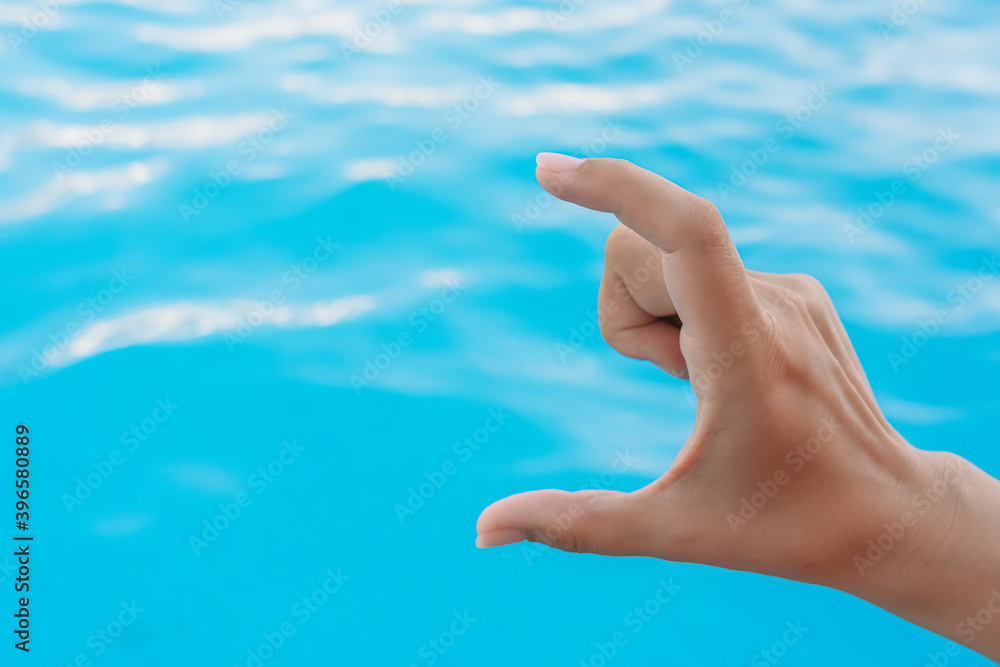 Closeup view horizontal photography of 1 female hand forming gesture as if showing size of virtual invisible object with help of two fingers isolated on bright blue water bokeh background. Closeup view horizontal photography of 1 female hand forming gesture as if showing size of virtual invisible object with help of two fingers isolated on bright blue water bokeh background.