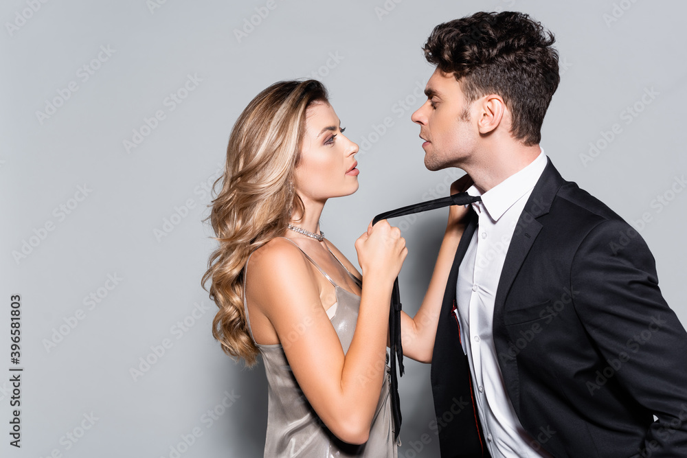 young woman holding tie on man in suit isolated on grey young woman holding tie on man in suit isolated on grey