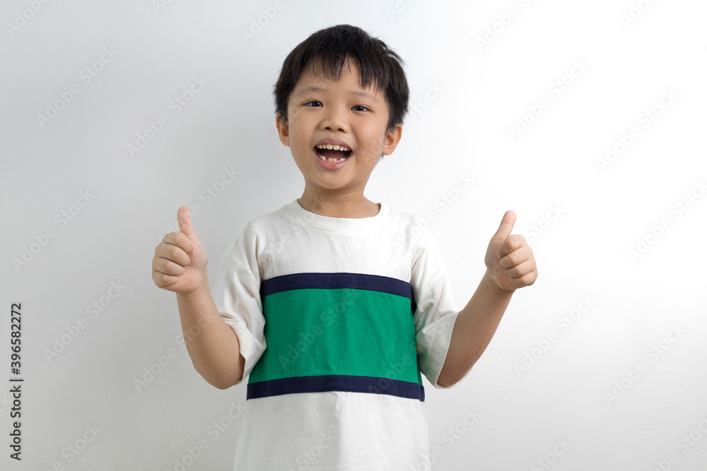 Cute little Asian boy showing thumbs up against a white background Cute little Asian boy showing thumbs up against a white background