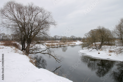 Photo the snow-covered river did not freeze in winter.The river flows in winter. Snow on the branches of trees. Reflection of snow in the river. Huge snowdrifts lie on the Bank of the stream. © ru4eek