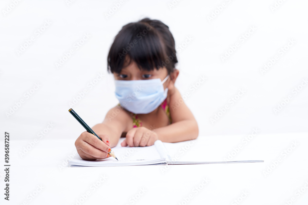 Close-up little girl hand writing in notebook, Wearing a protective face mask Close-up little girl hand writing in notebook, Wearing a protective face mask