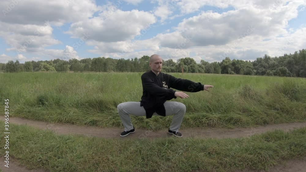 Caucasian man practicing tai chi Chinese martial arts exercise at the green park. Slow movement, deep breath relax calm peaceful environment Caucasian man practicing tai chi Chinese martial arts exercise at the green park. Slow movement, deep breath relax calm peaceful environment