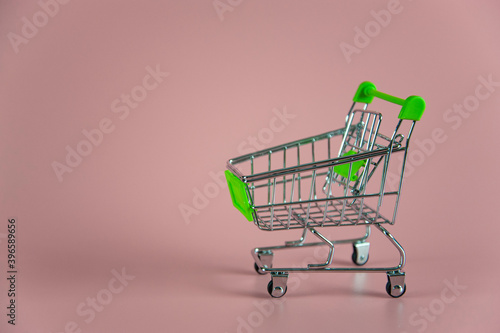 little empty shopping cart on pink background