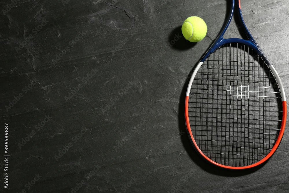 Tennis racket and ball on black table, flat lay. Space for text