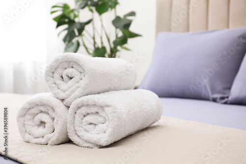 Rolled soft clean towels on bed indoors