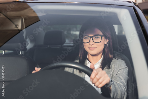 Fototapeta businesswoman looking ahead while driving car on blurred foreground