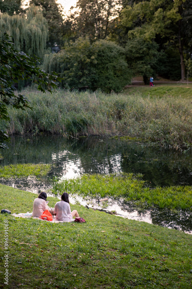 people resting near lake at city public park people resting near lake at city public park