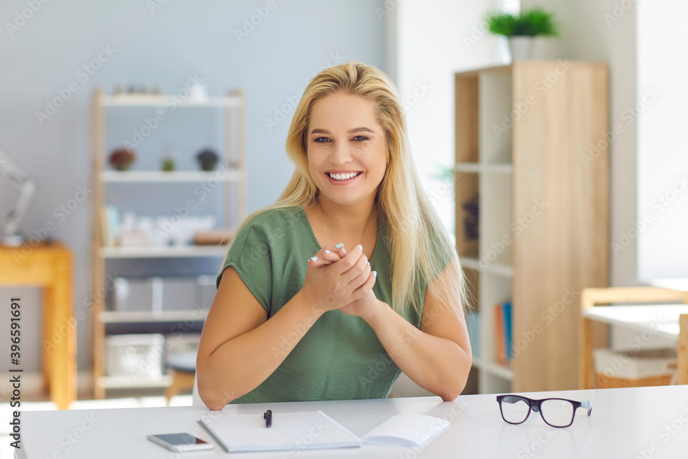 Smiling woman online conducts a business webinar through a video conference sitting in her office. Smiling woman online conducts a business webinar through a video conference sitting in her office.