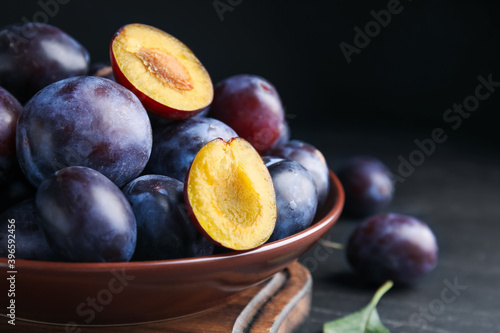 Fotótapéta Delicious ripe plums in bowl on black table, closeup