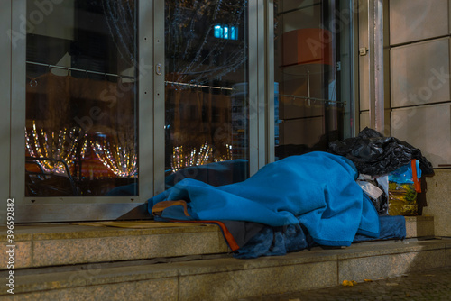 Homeless Man sleeping on sidewalk, Homeless man sleeping in winter, homeless man in sleeping bag on the street, sidewalk, Berlin unter den Linden, germany