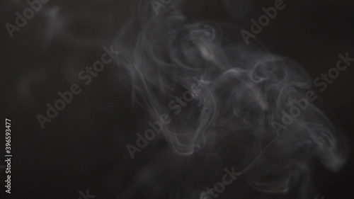 Slow motion shot of white smoke in front of the black background. Realistic Atmospheric Gray Smoke on Black Background. White Fume Slowly Floating Rises Up. Abstract Smoke isolated on black background photo