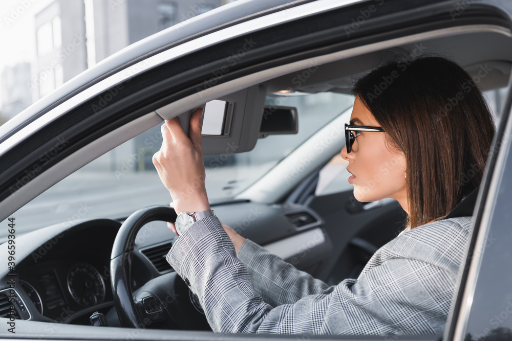 businesswoman adjusting rearview mirror while sitting in car, stock image businesswoman adjusting rearview mirror while sitting in car, stock image