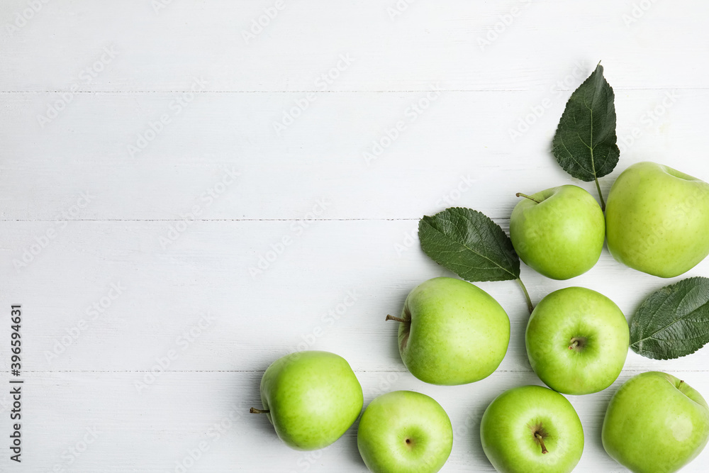 Obraz premium Ripe green apples and leaves on white wooden table, flat lay. Space for text