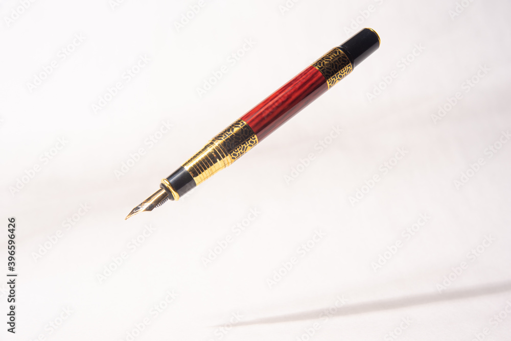 Antique fountain pen, fountain pen released in the air with drop shadow on light gray background, selective focus. Antique fountain pen, fountain pen released in the air with drop shadow on light gray background, selective focus.