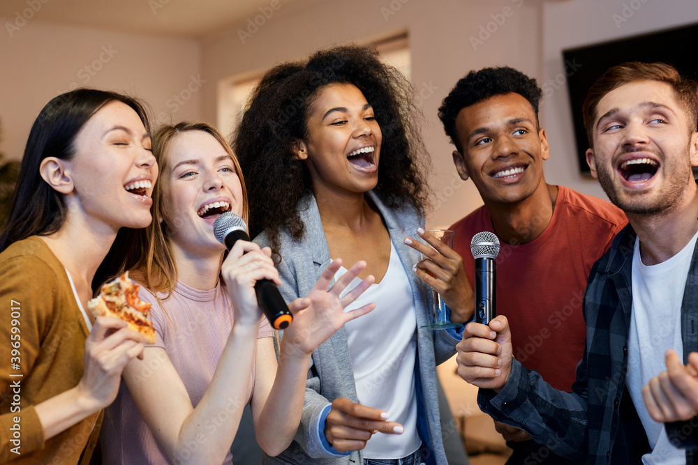© Kostiantyn - Sing it. Enthusiastic group of friends singing with microphone while playing karaoke at home, standing in the modern apartment © Kostiantyn - Sing it. Enthusiastic group of friends singing with microphone while playing karaoke at home, standing in the modern apartment