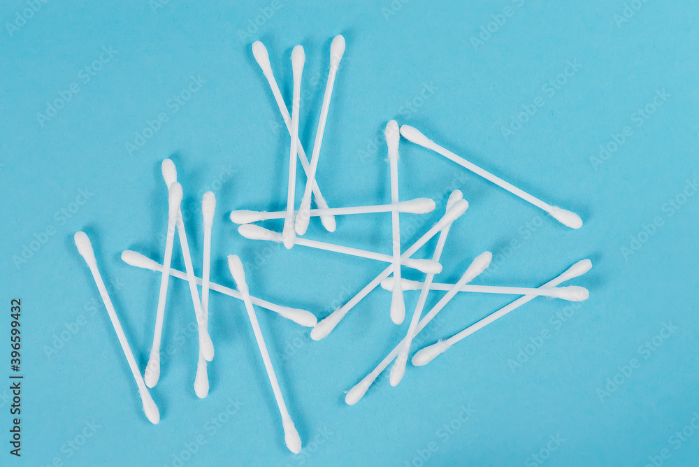 The white cotton buds with the white stem scattered on a blue background The white cotton buds with the white stem scattered on a blue background