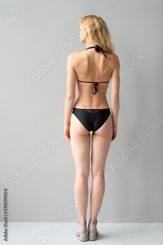 Attractive young blonde model in black swimsut posing in studio